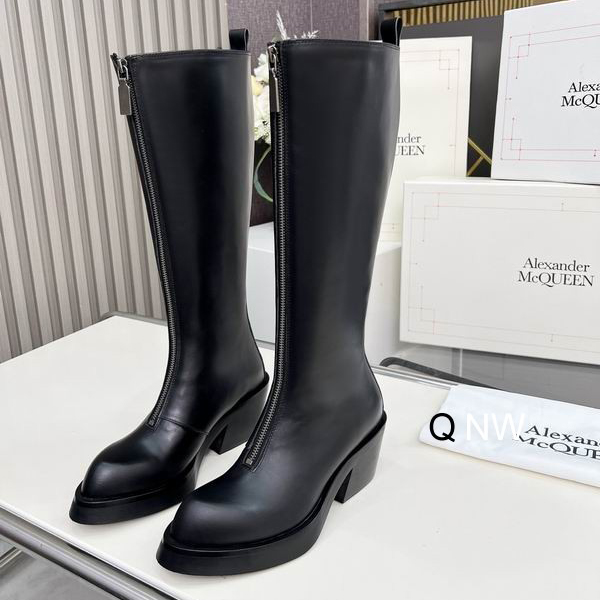 Pair of Alexander McQueen inspired black leather knee-high boots with a front silver zipper and chunky block heels on a white surface.