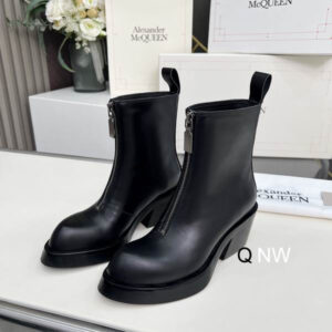 A pair of Alexander McQueen inspired black leather ankle boots with a central silver zipper, a solid black block heel, and a pull tab at the back, displayed on a white surface.