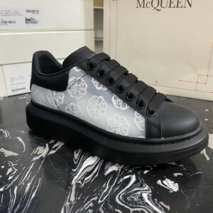 black and white Alexander McQueen Oversized Sneakers featuring a sheer white lace overlay with a floral motif, black leather details, and a thick black rubber sole.