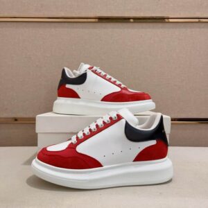 Pair of White Alexander McQueen-style oversized sneakers with Red suede paneling and a Black leather heel tab, resting on a white box. The sole is thick, white, and chunky.