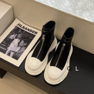 Front view of a pair of Alexander McQueen Tread Slick Boot Black White highlighting the central silver zipper and white toe cap.