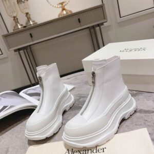 A pair of Alexander McQueen inspired white leather ankle boots with a central silver zipper and a very chunky, ridged white platform sole, displayed on a shoe box.