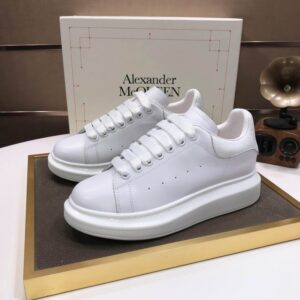 A pair of inspired Alexander McQueen oversized sneakers in all-white leather with matching thick white soles, shown from a top-down and side perspective.