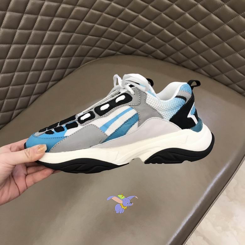 Amiri Bone Runner Light Blue Grey Black sneakers featuring black leather bone appliques on a mesh and suede upper, held against a quilted background.