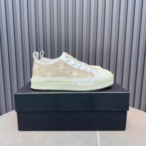 Side view of Amiri Star Court Low "Cream Tan" sneakers on a black box, featuring canvas uppers with leather star appliqués.