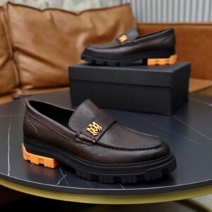 Close-up of the Amiri Lug Sole Loafer Brown Orange resting on its black shoe box highlighting the gold MA logo hardware.