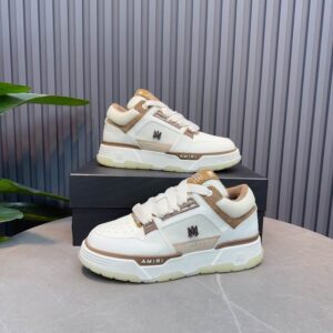 Pair of Amiri MA-1 sneakers in white and brown leather and suede featuring a chunky silhouette, thick white laces, and MA monogram hardware on a black box.