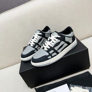 Side-view close-up of Amiri Skel Top Low Black Grey sneakers showing grey leather bone appliqués on a black leather upper with a silver AMIRI hangtag.