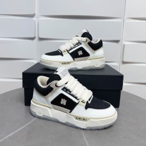 A pair of black and white Amiri Skel Top Low sneakers with white bone-shaped overlays on black suede, featuring a thick white rubber sole and black mesh details.
