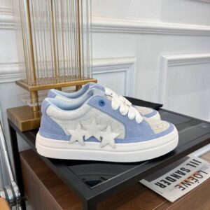 Side view of Amiri Skel Top Low sneakers in baby blue suede and white leather with star and bone shaped overlays on a white platform sole.