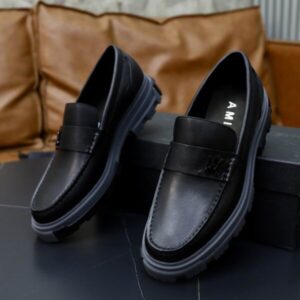 Side view of Amiri Black Leather Lug Sole Loafers on a black box with a grey chunky sole.