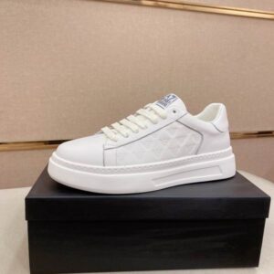 A hand holding a white Armani-inspired platform sneaker with embossed eagle logos on the side panel.