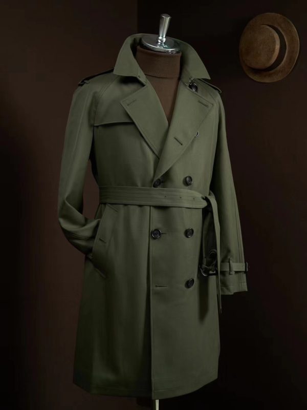 A midi-length, slim-fit double-breasted trench coat in army green wool featuring raglan sleeves, a belted waist with leather buckles, and a structured silhouette.