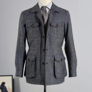 A sharp, grey technical fabric safari jacket with four utility pockets displayed on a hanger against a green curtain backdrop.