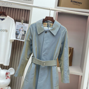 A mid-length Burberry Kensington trench coat in a muted slate blue-grey color, featuring a double-breasted button layout and a belted waist.