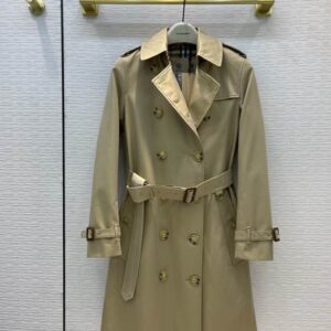 A slim-fitting black Burberry Chelsea trench coat featuring a double-breasted front, belted waist, and signature check-patterned lining under the collar.
