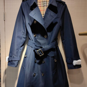 Women's long black double-breasted trench coat with visible gold buttons and belt hardware, featuring a full classic tan and red checkered interior lining.