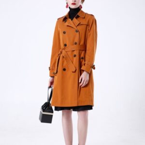 A midi-length, 10-button double-breasted trench coat in a cotton-poly blend featuring storm flaps, a belted waist with a leather buckle, and a structured turn-down collar.