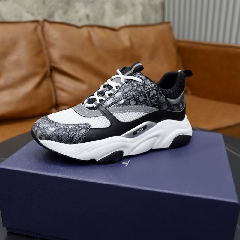 DIOR B22 sneakers with grey crocodile-embossed leather and white mesh on a black marble table in front of a blue Dior box.