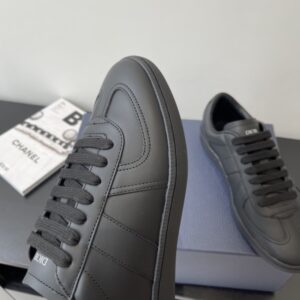 Top-down view of a pair of DIOR B27 low-top sneakers in all-black smooth leather resting on a navy blue Dior shoebox.