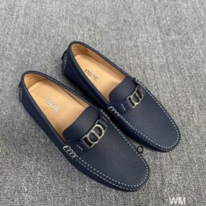 Pair of Dior Navy Blue Grained Calfskin Loafers with white stitching and silver CD buckle on a grey surface