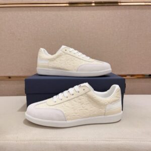 A pair of Dior B01 White and Cream Embossed Leather Sneakers displayed on a blue box, featuring cream monogrammed leather and white suede accents.