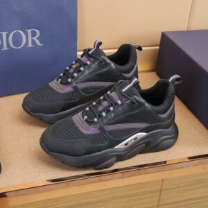 A close-up of a Dior B22 sneaker featuring black mesh and leather uppers with iridescent purple metallic stripes and a thick, wavy black midsole with a silver Dior logo insert.