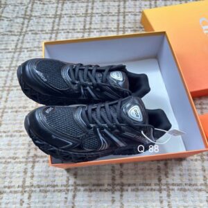 Top-down view of a pair of Dior B30 Low-Top Sneakers in black mesh and technical fabric resting inside an orange and white box.