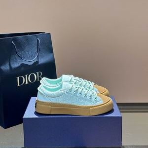 Side profile of Dior Mint Green Oblique Canvas B33 Low-Top Sneakers with a tan gum sole on a blue display box.