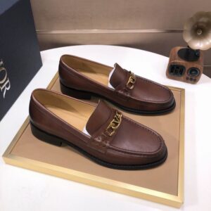 Pair of dior Classic Gold Hardware Leather Loafers in coffee brown displayed on a gold-rimmed tray.
