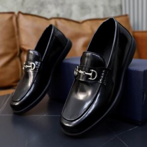 Top-down view of Dior Explorer Loafers in Polished Black with a silver horsebit buckle and chunky black soles, displayed on a dark grey table with branded packaging.