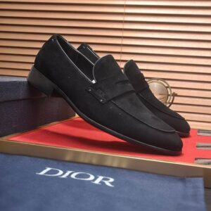 Side-profile view of Dior Granville Loafers in Black Suede resting on a red display mat with a blue branded dust bag and box in the background.