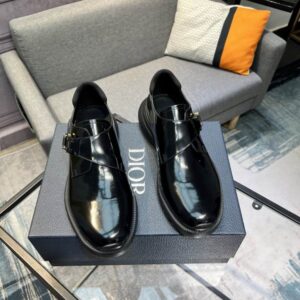 A pair of Dior-Inspired Polished Leather Buckle Loafers in Obsidian Black resting on a navy blue branded box, highlighting the high-shine finish and buckle.