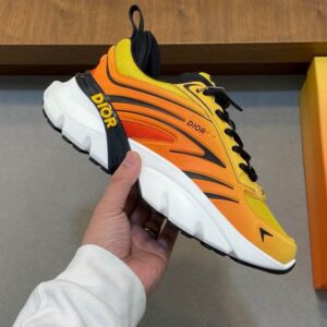 DIOR Vibe sneakers featuring a yellow and orange gradient mesh upper with black accents and a thick white midsole, displayed on a grey surface.