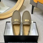 A pair of Dior Coffee Brown Gold Hardware Leather Loafers placed on a golden frame, featuring rich brown leather and interlocking gold hardware.