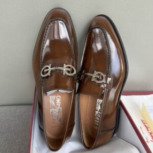 Top-down view of Ferragamo Gancini Loafers in hickory brown patent leather inside a red brand box.