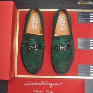 Top-down view of Ferragamo Emerald Green Suede Gancini Loafers with gunmetal hardware on a red display board.