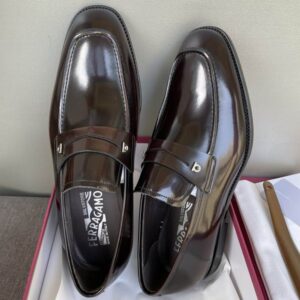 op and side views of burgundy patent leather loafers with silver hardware sitting on a grey surface next to a red shoebox.