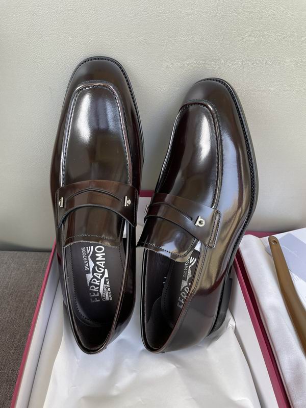 op and side views of burgundy patent leather loafers with silver hardware sitting on a grey surface next to a red shoebox.