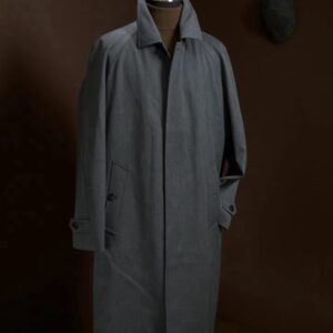 A midi-length, single-breasted coat in grey wool featuring raglan sleeves, a hidden front closure, and a clean, streamlined silhouette.