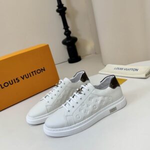 Pair of white LV Trainer style sneakers with black Monogram graphic overlays, thick white sole, displayed at an elevated angle showing the laces and tongue tag.