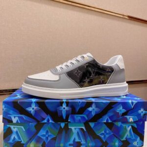 A pair of grey and white Louis Vuitton Monogram Paneled Court Sneakers, showcasing the leather paneling, perforated toe box, and the glossy black Monogram print on the side panel.