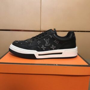 black low-top sneakers with dark grey monogram canvas side and toe panels, black laces, and a thick, layered black and white rubber sole
