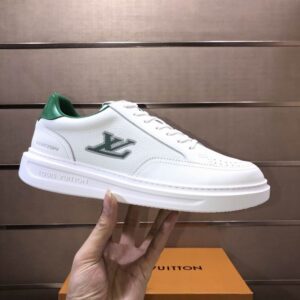 white low-top sneakers with a thick white sole, green heel tab, and inspired Louis Vuitton-style LV logo on the side.