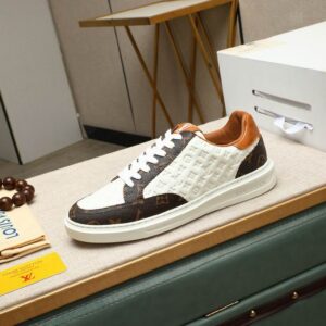 Low-top sneakers featuring brown monogram-inspired canvas and white embossed leather panels with a tan collar and white sole.