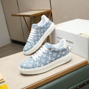 Pair of light blue denim low-top sneakers featuring a white monogram-inspired pattern, white laces, and a thick white ribbed platform sole.