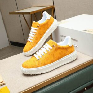 marigold orange canvas sneakers with a subtle monogram pattern, white laces, and a thick white serrated platform sole displayed on a cushioned table.
