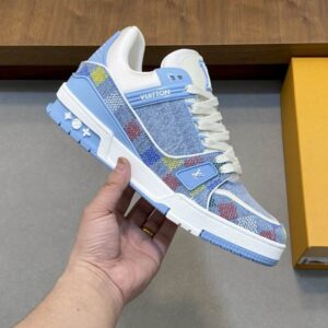 Louis Vuitton Trainer Sneakers in light blue denim with a colorful Damier pattern on a grey background.