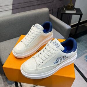 A pair of Louis Vuitton Trainer Sneakers in light blue denim with colorful patchwork details on a grey surface.