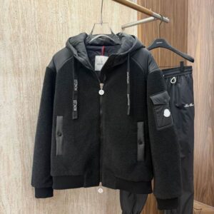 Men's black teddy fleece jacket with technical nylon shoulder and hooded panels, branded drawstrings, and a zip closure, displayed on a hanger.